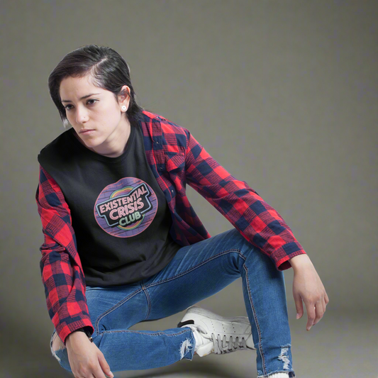 Person wearing a red and black plaid shirt over a black t-shirt with a graphic design, sitting on the floor against a white background.